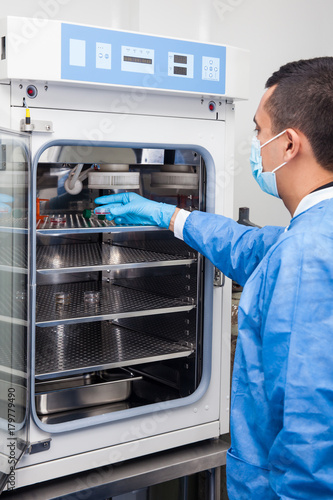 Young laboratory researcher introducing a petri dish into an incubator