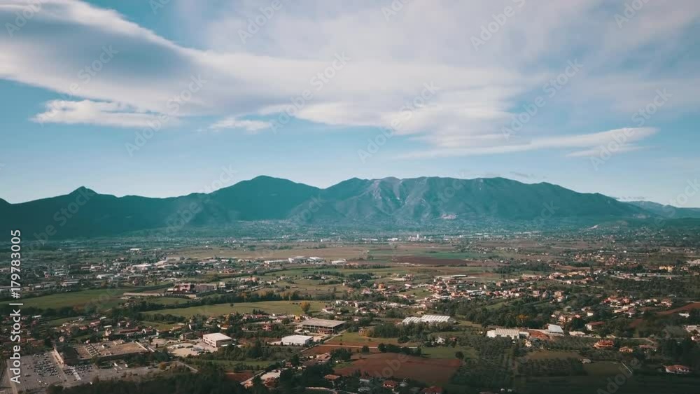 Video from above, aerial view of an Italian countryside with clouds and beautiful mountains in the background. Video from above, aerial view of an Italian countryside with clouds and beautiful mountains in the background.