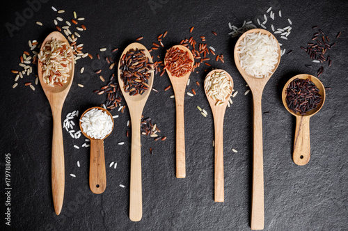 Mixed rice, White rice, Jasmine rice, Black rice, Brown rice, Riceberry and Raw rice in wooden spoon over black desk background