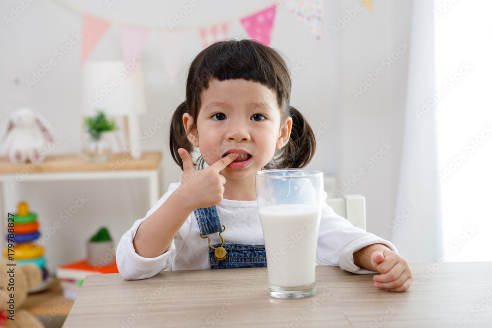 Adorable baby girl with dringking milk with milk mustache holding glass of milk Adorable baby girl with dringking milk with milk mustache holding glass of milk
