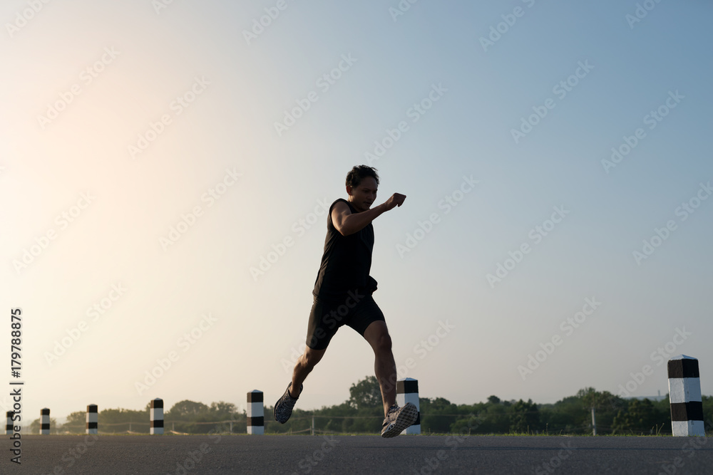 Asia young man running in the time during sunrise on dam road exercise.Healthy lifestyle