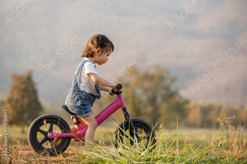 Happy child riding a bike. Little girl on a pink bicycle. Healthy preschool children summer activity. Kids playing outside. Little girl learns