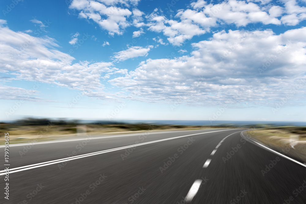 empty asphalt road with blue sea in blue sky