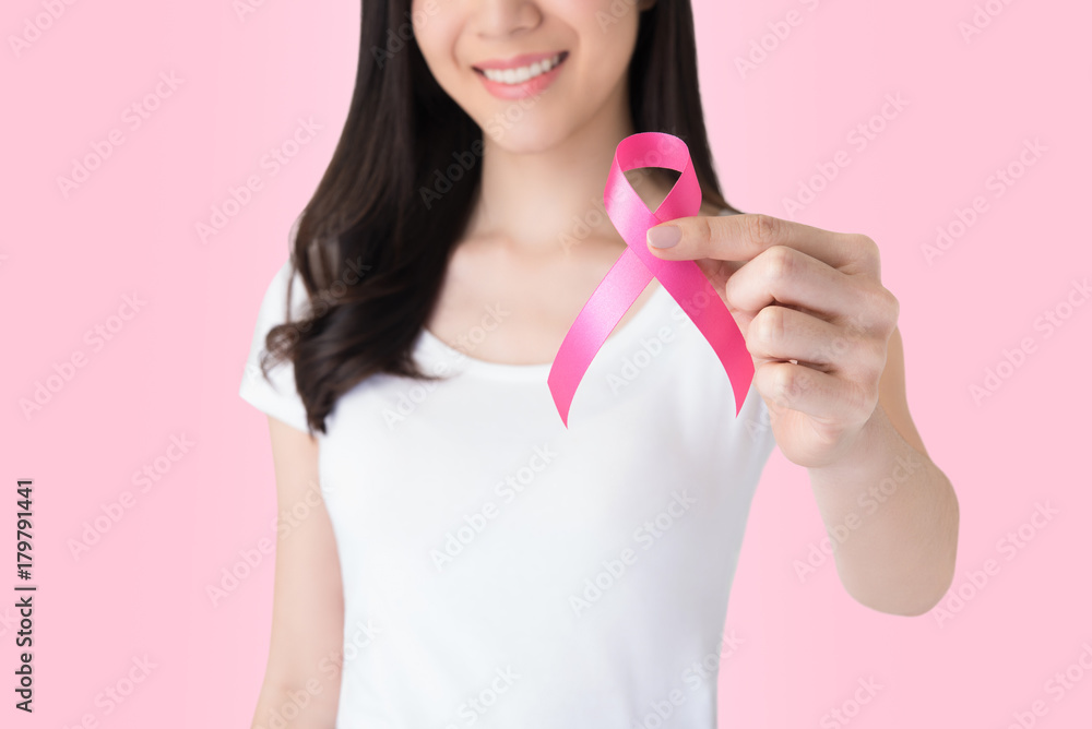 Smiling woman in white t-shirt giving satin pink ribbon, supporting symbol of breast cancer awareness campaign in October Smiling woman in white t-shirt giving satin pink ribbon, supporting symbol of breast cancer awareness campaign in October