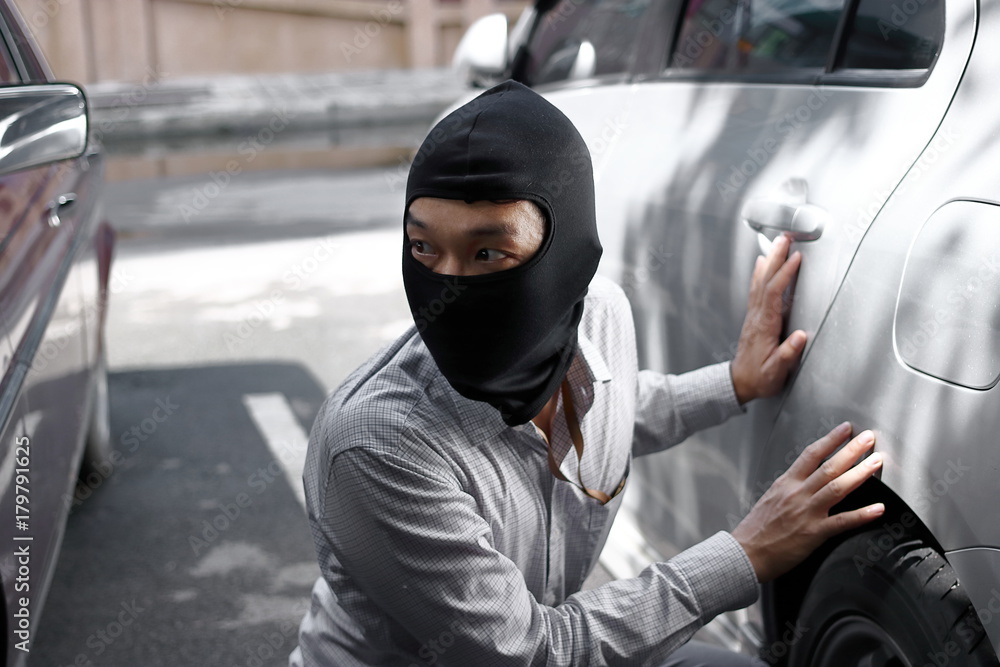 Masked burglar wearing a balaclava ready to burglary against car background. Insurance crime concept. Masked burglar wearing a balaclava ready to burglary against car background. Insurance crime concept.