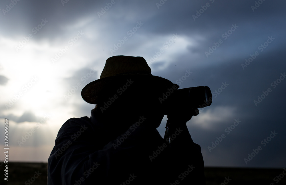 silhouette of a man with a camera on a sunset background