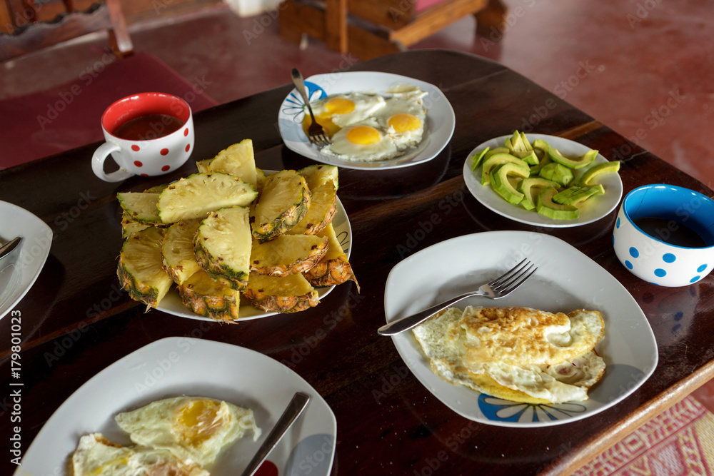 Breakfast table with fried eggs, scrambled eggs, pineapple, avocado, coffee Breakfast table with fried eggs, scrambled eggs, pineapple, avocado, coffee