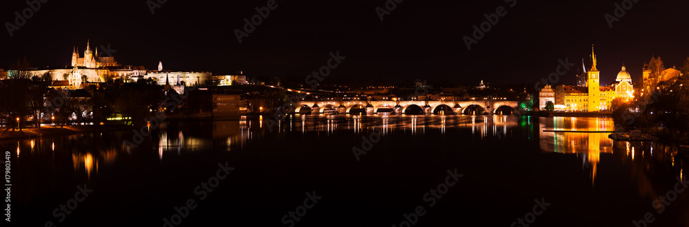 Prague castle and Charles bridge night panorama with city light with reflection in river