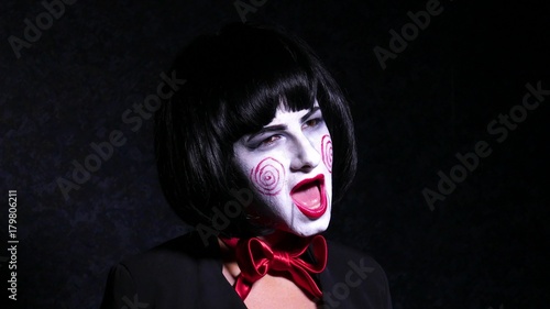 pretty woman in horror style make up sings a song on dark background