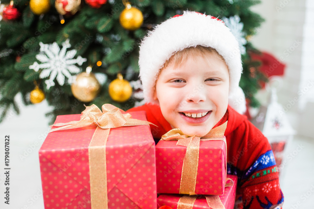 Closeup portrait of excited cute little child in holiday christmas interior. Happy adorable kid posing with many presents in red wrapping paper. Horizontal color photography. Closeup portrait of excited cute little child in holiday christmas interior. Happy adorable kid posing with many presents in red wrapping paper. Horizontal color photography.