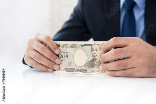 Businessman hands holding money, Japanese Yen currency, at the table