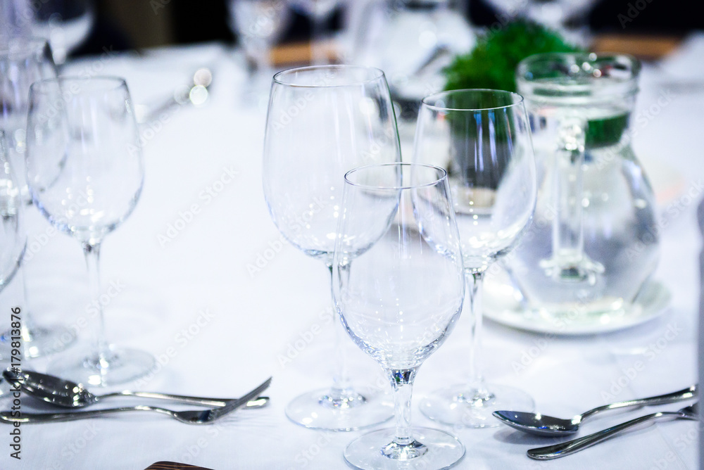 Transparent glasses on a banquet table with spoons and forks. Transparent glasses on a banquet table with spoons and forks.