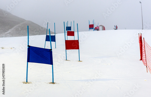 Фотография Children skiing slalom racing track with blue and red gates.