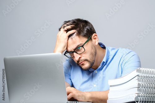 Pensive sad man sitting at the table with laptop