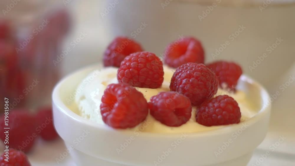 large juicy berries of raspberries fall in a plate with white yogurt. delayed shooting. large salt berries are appetizing. hd large juicy berries of raspberries fall in a plate with white yogurt. delayed shooting. large salt berries are appetizing. hd
