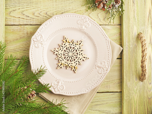 Christmas background. Wooden tray with rough rope handle set with plate and napkin, wooden snowflake. Spruce branches and snow-covered bump