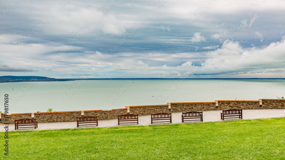 Park with lake view. Bench with walk path and cloudy sky Park with lake view. Bench with walk path and cloudy sky