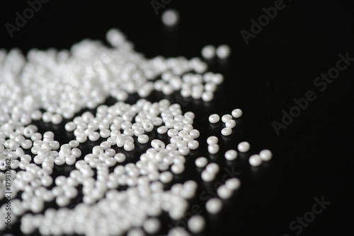 White seed beads scattered on a dark background