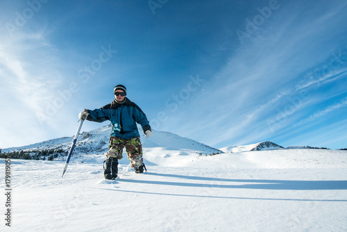climber with an ice ax walks in the snowy mountains