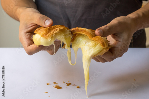 croissant with melting cheese in mans hands