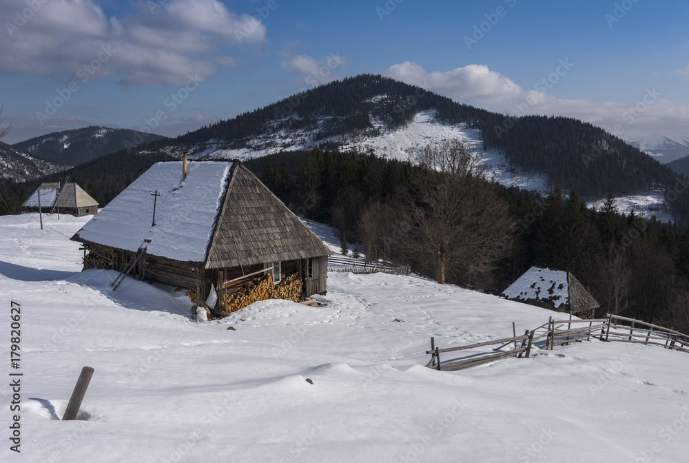 Old wooden house and combined firewood high in mountains in winter