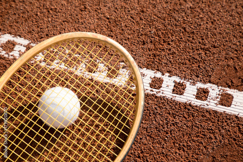 tennis raquet with tennis ball on ash court