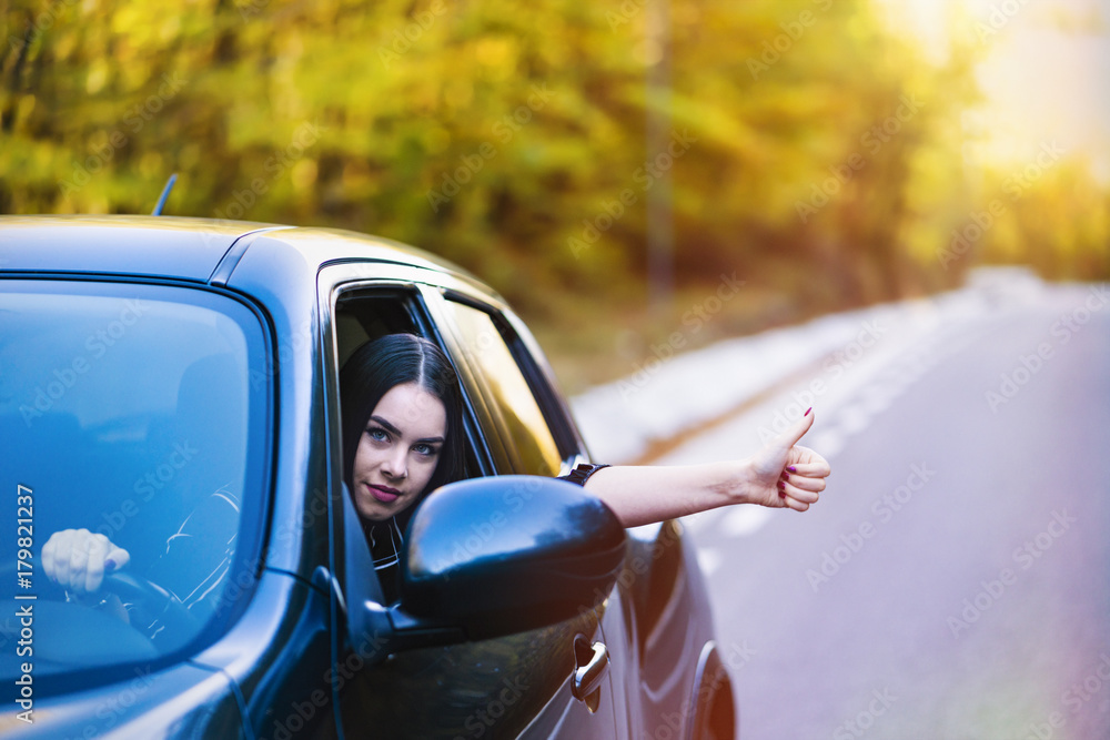 A beautiful brunette driver shows the ok sign on the car window A beautiful brunette driver shows the ok sign on the car window