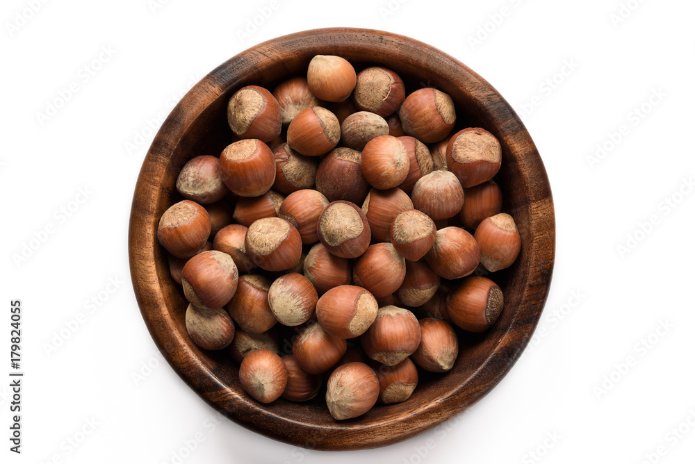 Hazelnuts in a wood bowl and loose isolated over white background. Hazelnuts in a wood bowl and loose isolated over white background.
