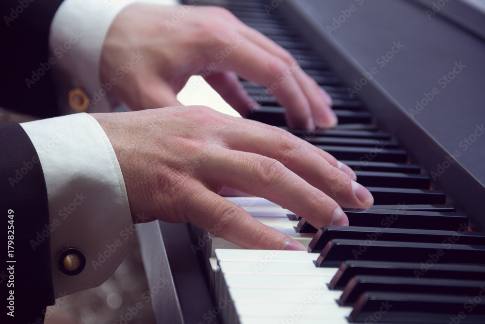 Obraz premium man's hands playing on a piano at the concert