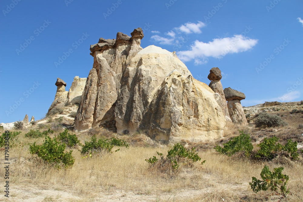 Rocks looking like mushrooms dramatically lit by a sun in Chavushin in Cappadocia, Turkey.