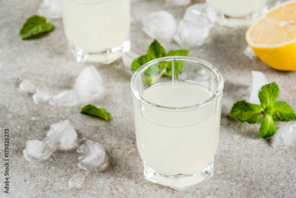 Traditional italian alcoholic homemade beverage, lemon liqueur limoncello with fresh citrus, ice and mint, on grey stone table, copy space Traditional italian alcoholic homemade beverage, lemon liqueur limoncello with fresh citrus, ice and mint, on grey stone table, copy space