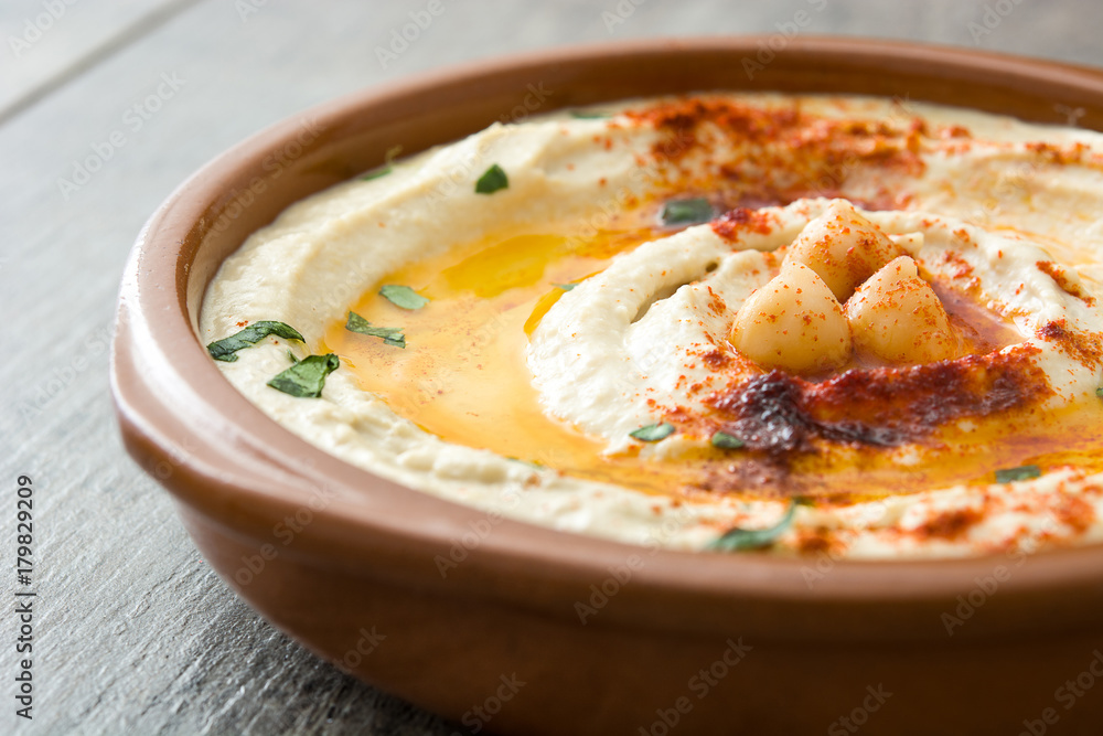 Chickpea hummus in bowl on wooden table. Chickpea hummus in bowl on wooden table.
