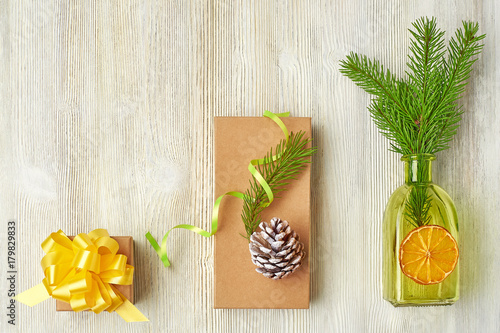 Christmas collection of tree branches, cones, green bottles, orange slice, gift box Kraf on a light wooden background photo