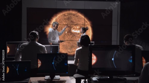 Two scientists discuss the trajectory of the shadow of the solar eclipse moving along the surface of the Earth. Elements of this image furnished by NASA.