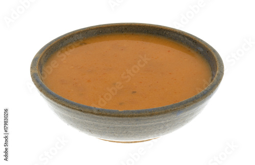 A serving of salmon bisque soup in an old stoneware bowl isolated on a white background.