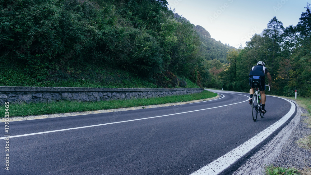 Fototapeta premium Middle aged man in lycra tackles a tough climb in the Italian alps