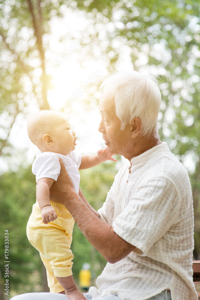 Fototapeta premium Grandfather with grandson sitting at outdoor bench.