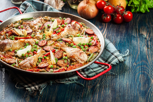 Traditional paella with chicken legs  sausage chorizo and vegetables served in paellera