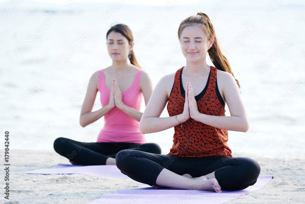 Young healthy asian women practicing yoga in namaste posture on the beach, healthy lifestyles, wellness, well being