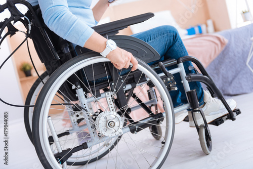 Wheelchair. Paralyzed woman sitting in a wheelchair and wearing a watch and having jeans and sneakers on