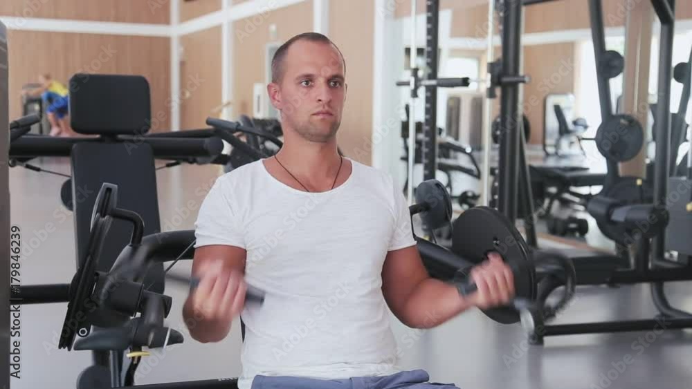 The man trains biceps in the gym The man trains biceps in the gym