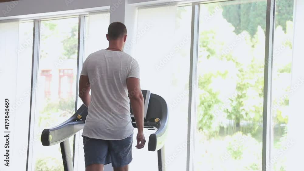 Silhouette of man running on the treadmill and looking into the large window. Silhouette of man running on the treadmill and looking into the large window.