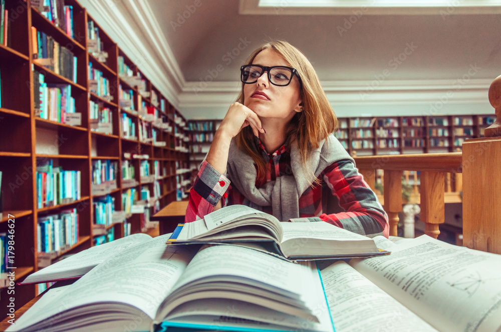 Thinking casual stylish student girl wears glasses studying hard with books in the library, education concept Thinking casual stylish student girl wears glasses studying hard with books in the library, education concept