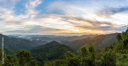 Mountain forest landscape under sunrise sky with clouds. © chanwitohm