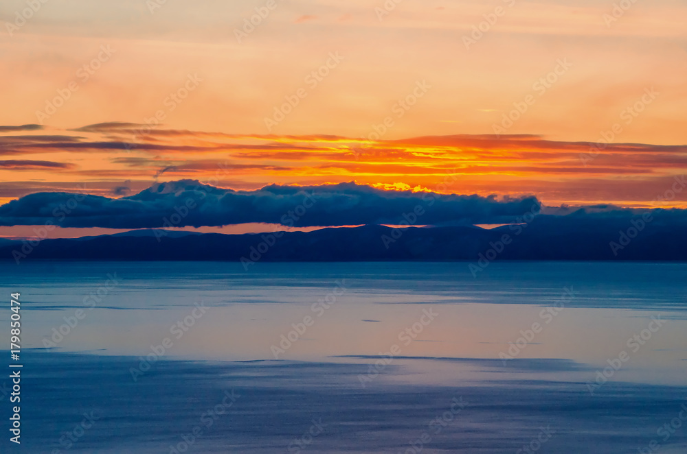 Beautiful orange sunset over the lake with mountain