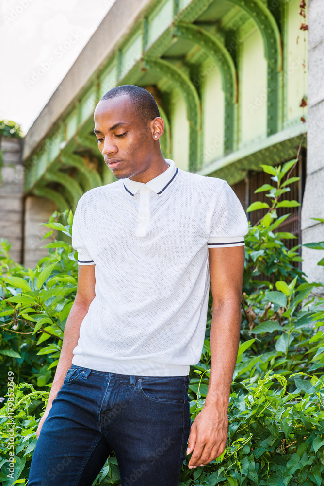 Portrait of Young African American Man in New York. Wearing white Polo shirt,  blue jeans, a