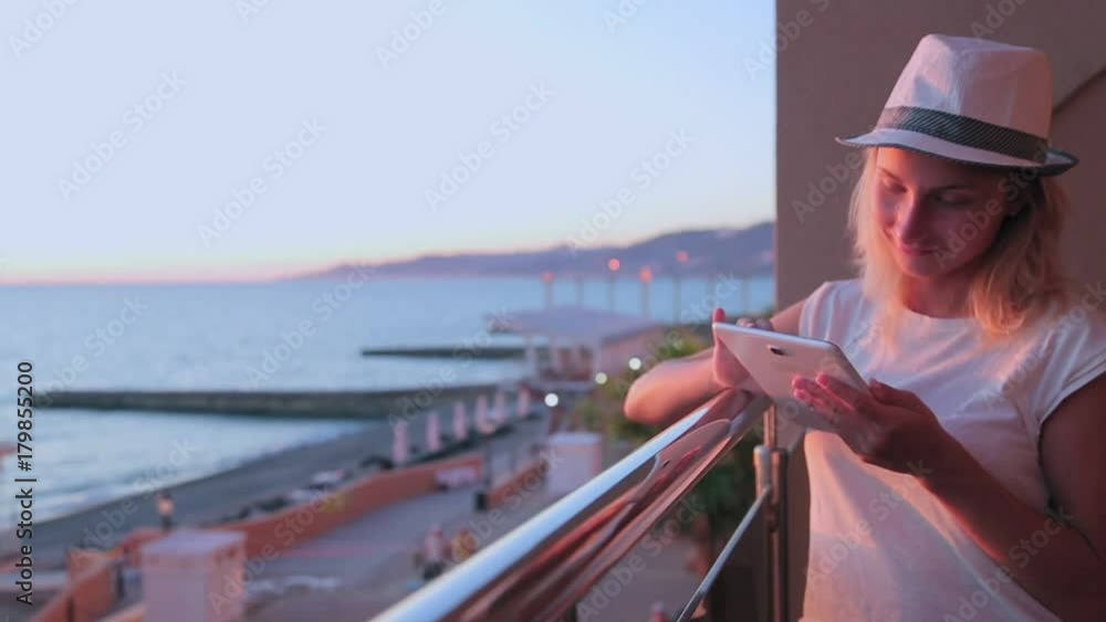 Young woman with long hair using tablet. At sunset seen a lake or the sea Young woman with long hair using tablet. At sunset seen a lake or the sea