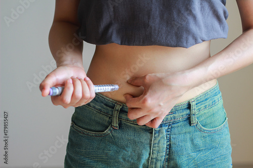 A diabetes patient is injecting insulin pen by herself.