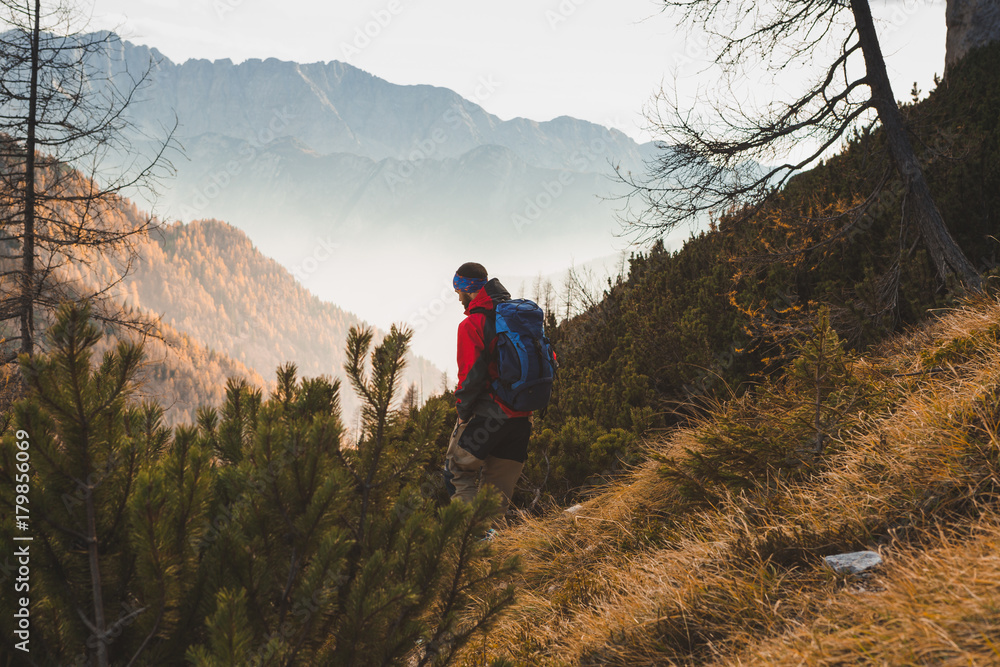Man traveler with backpack hiking towards mountain pass in Julian Alps, lifestyle outdoors