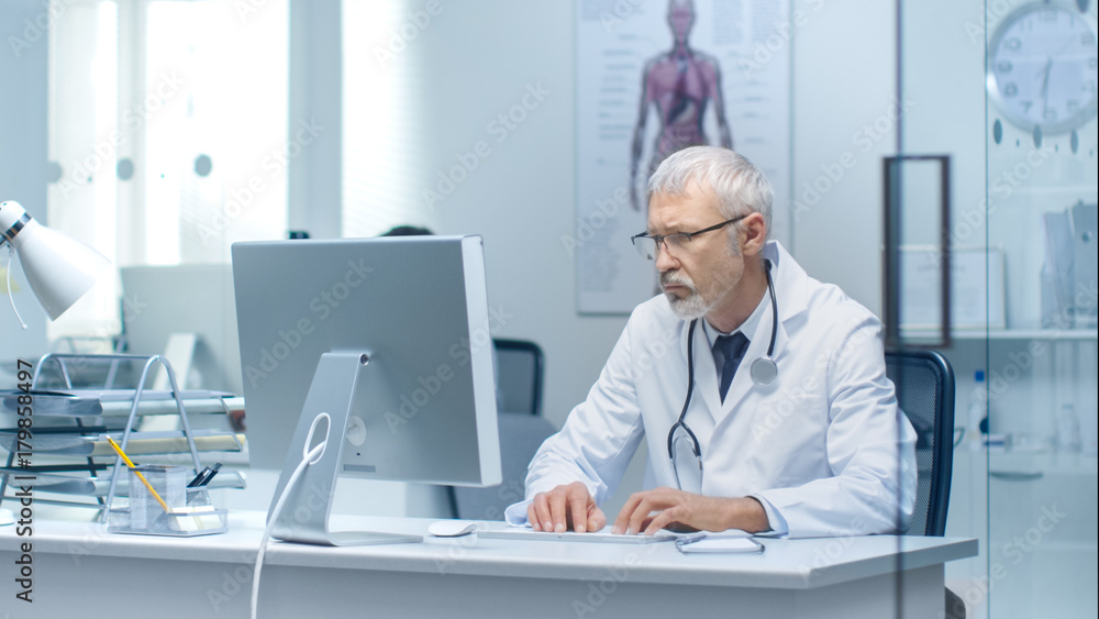 Senior Doctor and His Assistant Working on PC in Bright and Light Office. Senior Doctor and His Assistant Working on PC in Bright and Light Office.